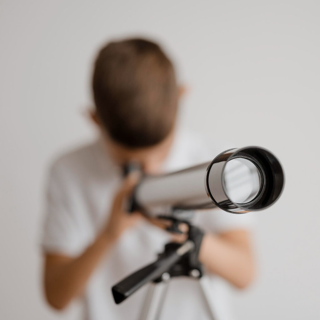 enfant regardant au travers d'une lunette astronomique